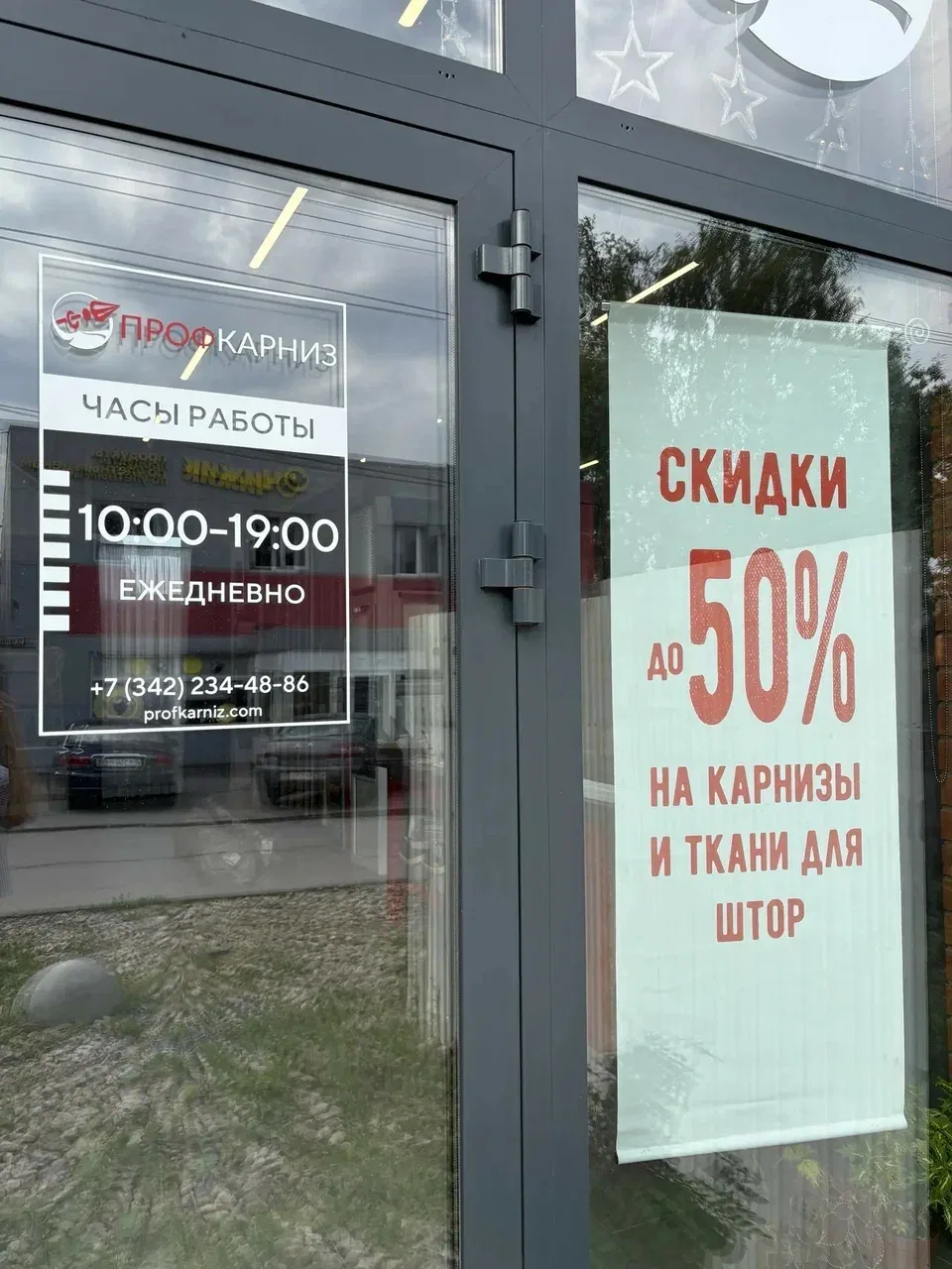 Вход в магазин — чёрная дверь с вывеской «ПрофКарниз» и режимом работы на стекле